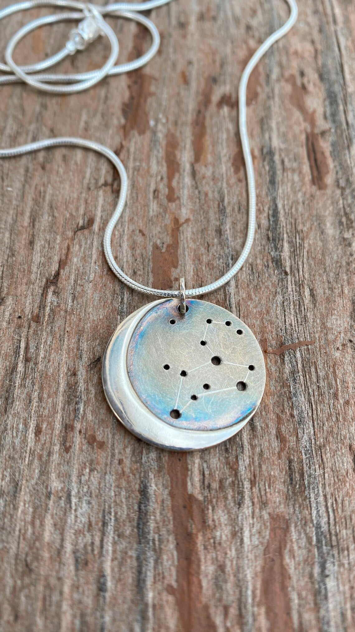 Embrace celestial beauty with our Silver Moon Zodiac Necklace. Each constellation represents a zodiac sign, custom-made just for you. Handcrafted from high-quality silver, this pendant features an oxidized night sky. The perfect birthday or holiday gift for astrology enthusiasts.