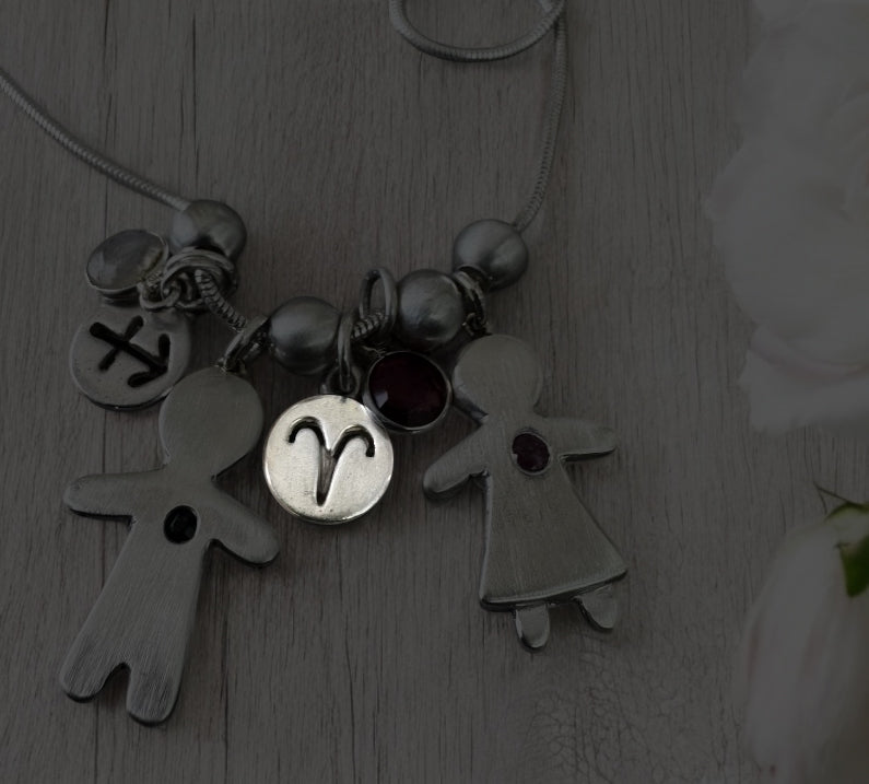 Handcrafted silver necklace with boy and girl charms, featuring blue and pink sapphires – personalized mother’s gift