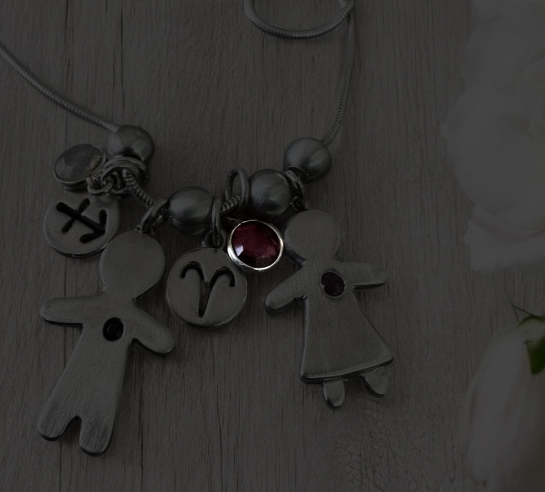 Handcrafted silver necklace with boy and girl charms, featuring blue and pink sapphires – personalized mother’s gift