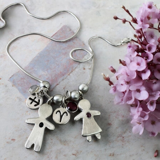 Handcrafted silver necklace with boy and girl charms, featuring blue and pink sapphires – personalized mother’s gift