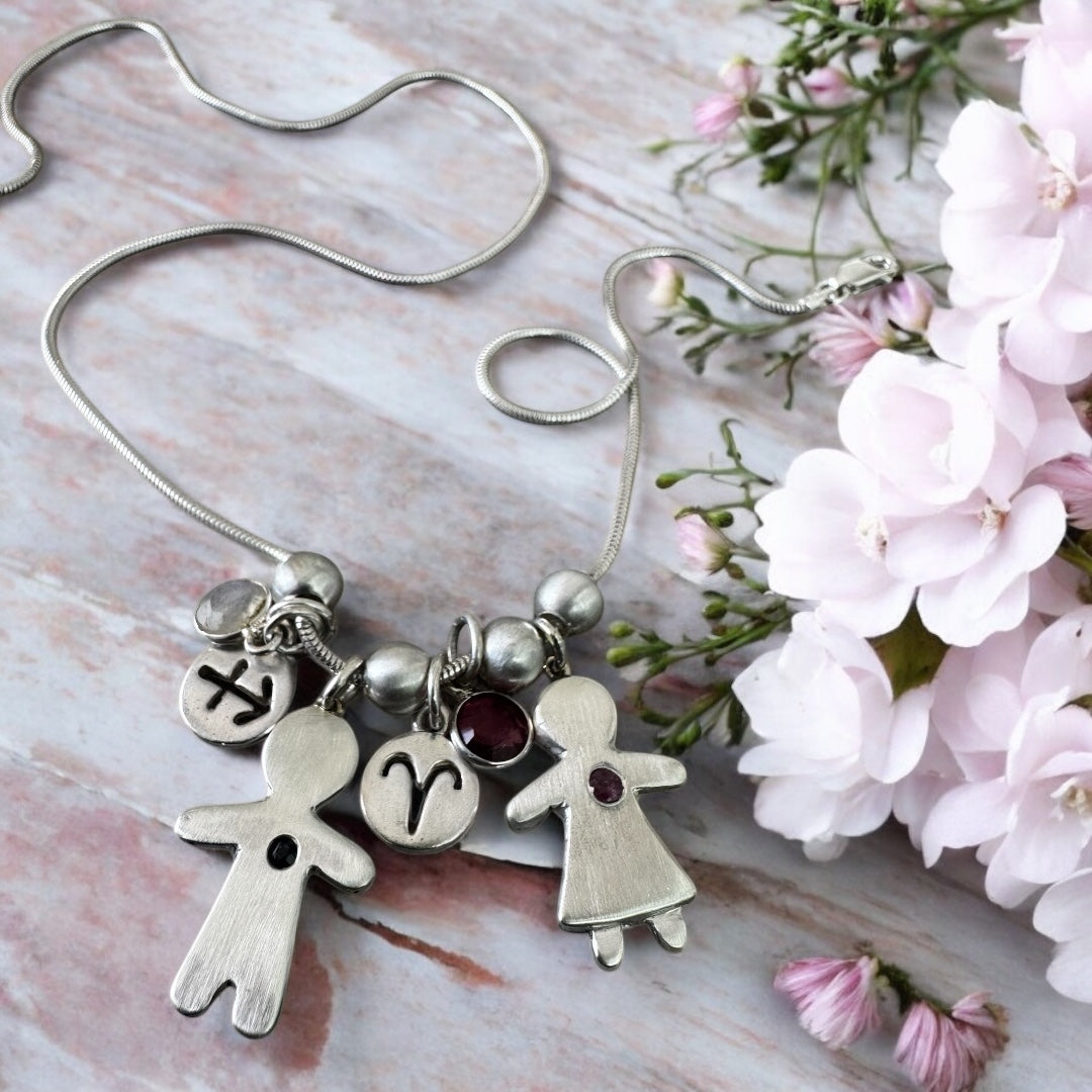 Handcrafted silver necklace with boy and girl charms, featuring blue and pink sapphires – personalized mother’s gift