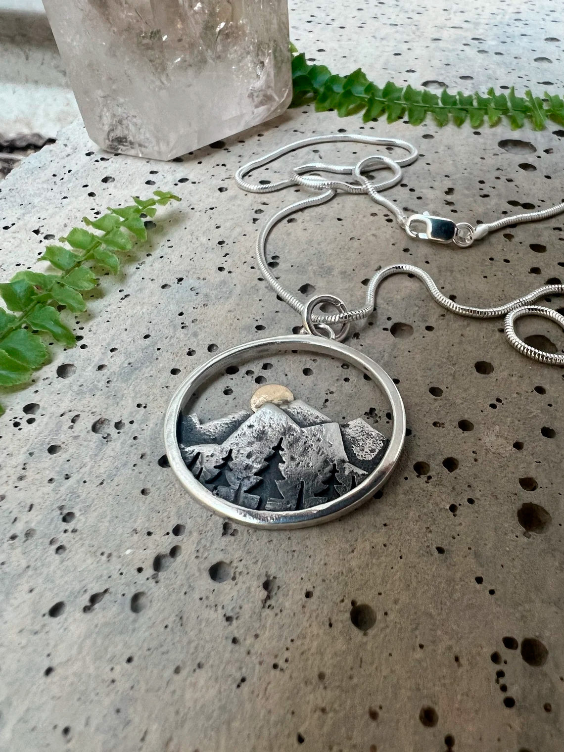 Embrace the beauty of the outdoors with our Sunset Mountain Necklace. Crafted in silver and 14k yellow gold, the 30 mm diameter pendant features a solid gold sun atop the mountains. Whether you’re biking, hiking, or skiing, this design celebrates the adventurous spirit of mountain lovers!