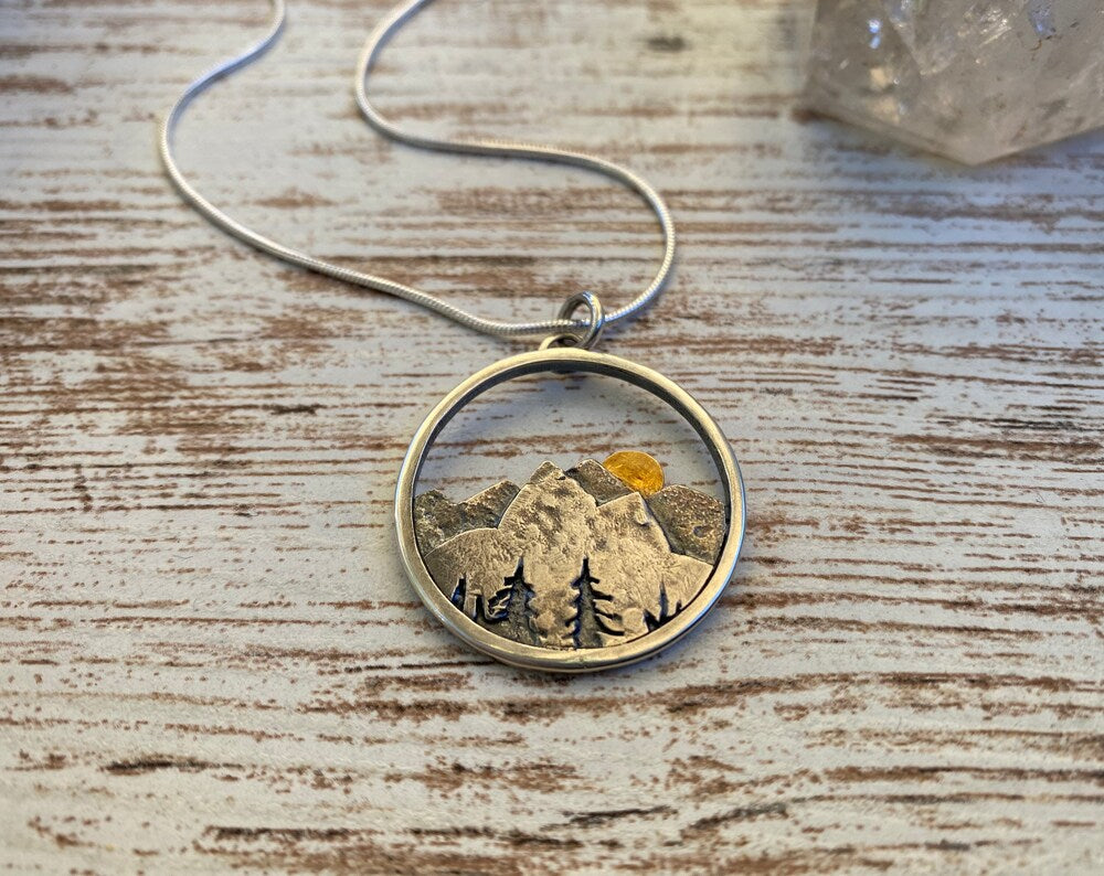 Embrace the beauty of the outdoors with our Sunset Mountain Necklace. Crafted in silver and 14k yellow gold, the 30 mm diameter pendant features a solid gold sun atop the mountains. Whether you’re biking, hiking, or skiing, this design celebrates the adventurous spirit of mountain lovers!