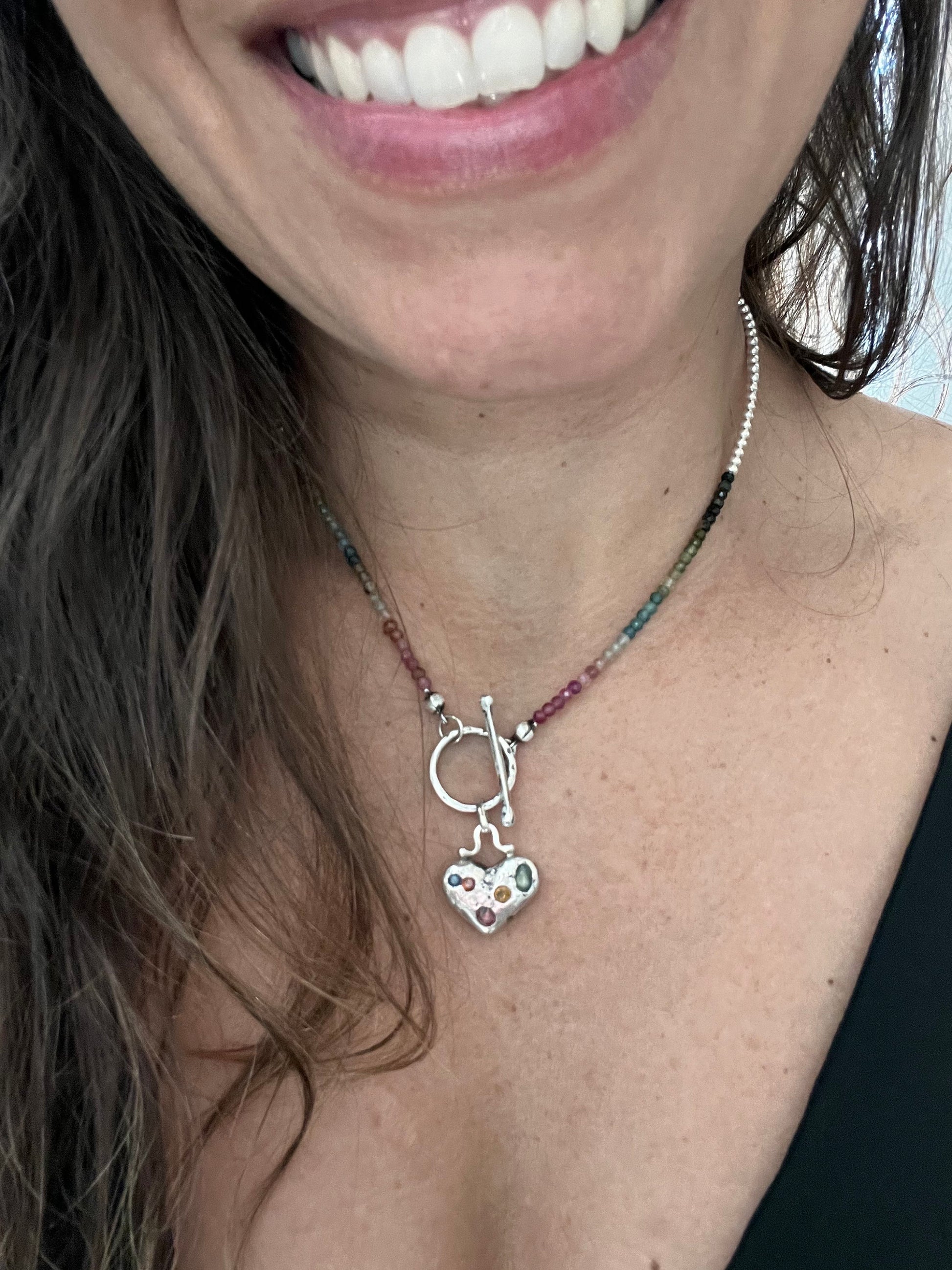 Discover our Colorful Heart Sapphire Necklace – a 15mm heart pendant adorned with seven ethically sourced sapphires, each representing a chakra. Crafted from recycled sterling silver using sand casting technique. A harmonious blend of elegance and energy.