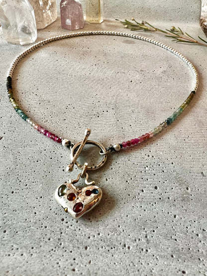 Discover our Colorful Heart Sapphire Necklace – a 15mm heart pendant adorned with seven ethically sourced sapphires, each representing a chakra. Crafted from recycled sterling silver using sand casting technique. A harmonious blend of elegance and energy.