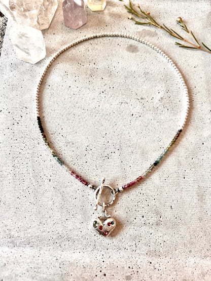 Discover our Colorful Heart Sapphire Necklace – a 15mm heart pendant adorned with seven ethically sourced sapphires, each representing a chakra. Crafted from recycled sterling silver using sand casting technique. A harmonious blend of elegance and energy.